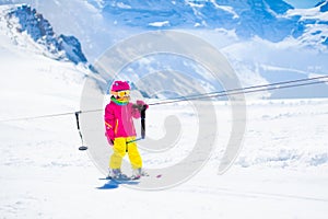 Child on ski lift in snow sport school in winter mountains