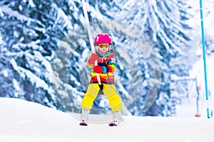 Child on ski lift in snow sport school in winter mountains