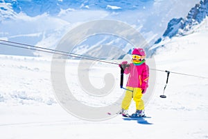 Child on ski lift in snow sport school in winter mountains