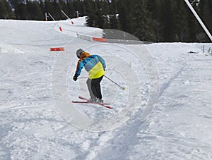 Child skier performs a high jump with the ski in Chopok, Slovakia. Winter season, colorful jacket. Small boy jumping on downhill