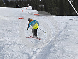 Detský lyžiar predvádza skok do výšky s lyžou na Chopku na Slovensku. Zimná sezóna, farebná bunda. Malý chlapec skákajúci z kopca