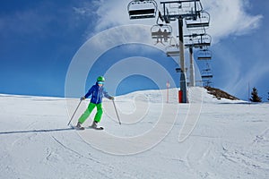 Child skiing fast under chairlift on snowy slope in mountains