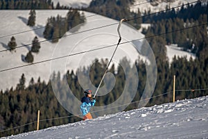 Child skiing in the snow. One Asian boy sitting on ski lift by grabbing the rope. Winter sport