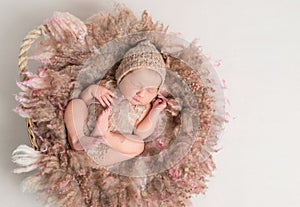 Child sleeping on furry pillow, in knitted suit