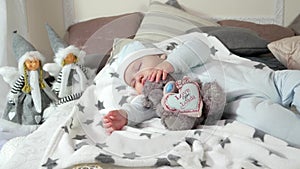 Child sleeping on parents` bed in a cozy atmosphere in the house, little boy asleep hugging a stuffed toy, sweet baby