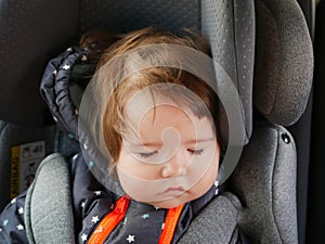 The child sleeps in a child car seat. child safety in the car. Sleeping baby while traveling