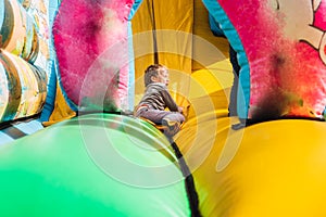 Child sliding down a colorful inflatable bounce castle having a great time