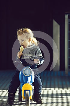 Child or small boy eating ice cream on toy bike