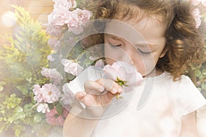 Child smelling flower on blurred hazy background photo