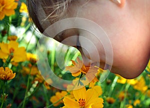 Child Smelling a Yellow Flower