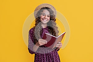 child smile with frizz hair read book on yellow background