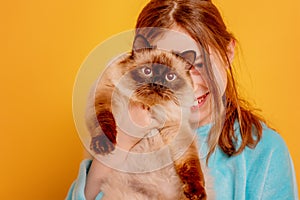 The child smiles with the animal. A teenage girl with a point cat