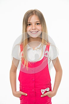 Child smiling with long blond hair. Small girl smile in pink jumpsuit isolated on white. Kid model in fashionable