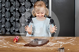 Child Smiling While Making Gingerbread Cookies with Cookie Cutters at Home