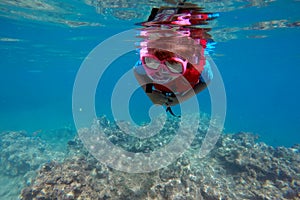 Child snorkeling dive over a coral reef