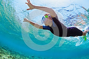 Child in snorkeling mask dive underwater in blue sea lagoon