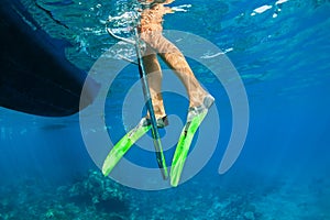 Child in snorkelling fins stand on divers boat ladder