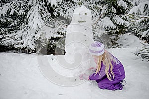 Child, snowman and winter forest