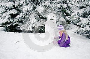 Child, snowman and winter forest