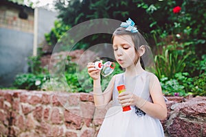 Child and soap bubbles. Little girl having fun with soap bubbles. Child little girl in a dress blows a soap bubble in the park.