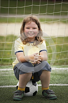 Child soccer football player. Boy with ball on green grass.