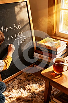 Child Solving Math Problems on Blackboard at Home