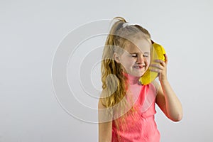 The child speaks in a banana phone. Little girl laughing and playing