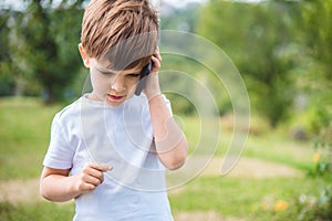 The child speaks on the phone in nature