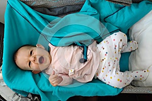 A child in a special cradle on the plane. Top view. Baby Yawns in bassinet lying at green plaid