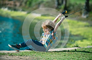 Child with spinner at river. Portrait of excited boy fishing. Boy at jetty with rod. Fishing concept.