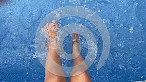 Child splashing feet in swimming pool water