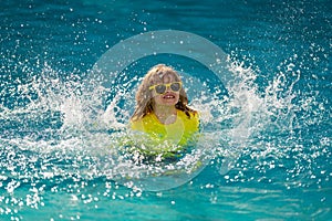 Child splashing in summer water pool. Kid splash in pool. Excited happy little boy jumping in pool, water fun. Kid