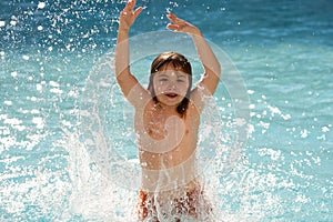Child splashing in summer water pool. Kid splash in pool. Excited happy little boy jumping in pool, water fun. Kid