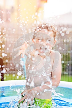 Child splashing water in inflatable garden pool