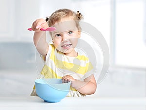 Child with spoon and bowl,girl eating.Kid`s nutrition
