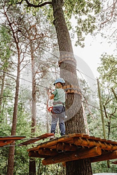 Child in sports equipment, a protective helmet stopped near a tree, holding a rope with his hands. Portrait of a brave boy