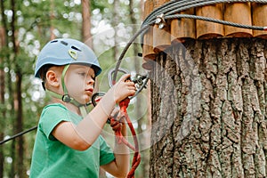 Child in sports equipment, a protective helmet stopped near a tree, holding a rope with his hands. Portrait of a brave boy