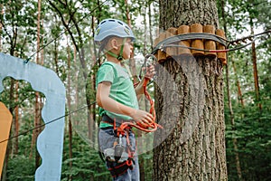 Child in sports equipment, a protective helmet stopped near a tree, holding a rope with his hands. Portrait of a brave boy