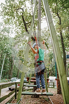 Child in sports equipment, a protective helmet stopped near a tree, holding a rope with his hands. Portrait of a brave boy