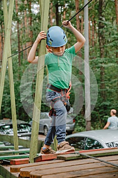 Child in sports equipment, a protective helmet stopped near a tree, holding a rope with his hands. Portrait of a brave boy