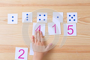 The child spreads cards with numbers to cards with dots. The study of numbers and mathematics photo