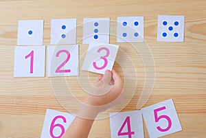 The child spreads cards with numbers to cards with dots. The study of numbers and mathematics