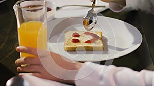 A child spreads sweet jam on toasted bread. Making a smiley face on toast. A housewife makes a breakfast sandwich.