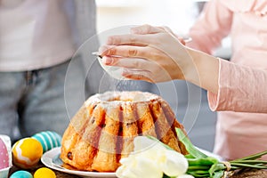 Child sprinkles flour powdered sugar on cake