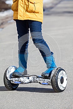 Child standing on groscooter, self-balanced two-wheeled urban mode of transportation, close up view with feet