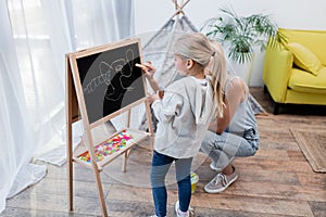 Child standing near mother with chalk