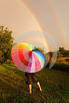 Child Standing in Rain With Colorful Umbrella Looking at Double