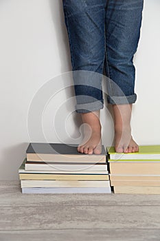 Child standing on stacks of books