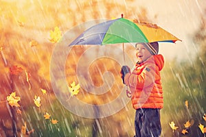 Child standing with umbrella in beautiful autumnal day