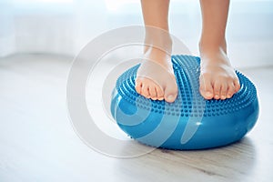 The child stands on a special inflatable pillow for the prevention and treatment of hallux valgus at home